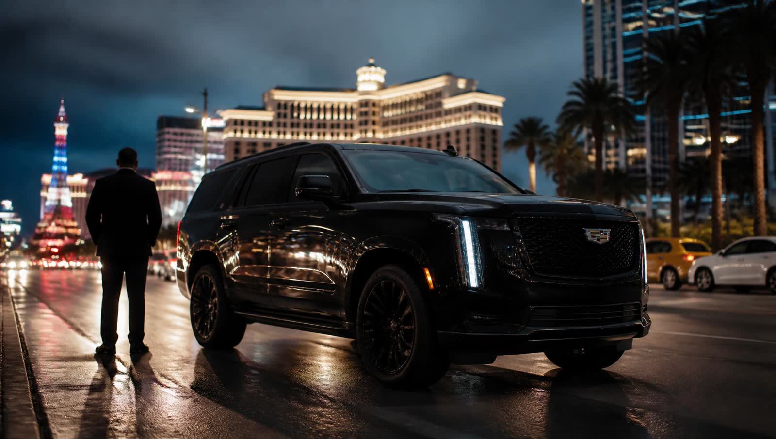 Black luxury SUV with a professional chauffeur waiting on a Las Vegas boulevard at dusk
